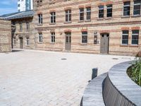 an empty courtyard outside an old building with many windows and plants on the ground next to it