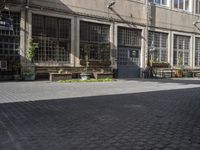 a row of wooden benches on a city street next to a building with many windows