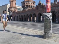 a woman walking down the middle of an empty city street in front of a brick building