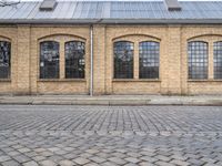 the outside of an old brick building is very large and it has two tall windows