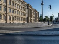 a street light next to an empty road in front of a building with a traffic light on top of it