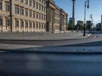 a street light next to an empty road in front of a building with a traffic light on top of it