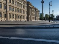 a street light next to an empty road in front of a building with a traffic light on top of it