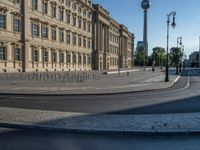 a street light next to an empty road in front of a building with a traffic light on top of it