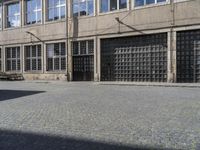 an empty street with benches and windows on one side and a sign on the other