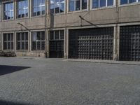 an empty street with benches and windows on one side and a sign on the other