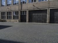 an empty street with benches and windows on one side and a sign on the other