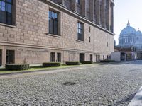 there is an empty stone street in front of buildings with domes in the background