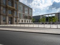 this is an outdoor area near buildings with glass windows on the sides, surrounded by a row of metal fences