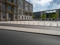 this is an outdoor area near buildings with glass windows on the sides, surrounded by a row of metal fences