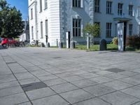 a sidewalk with a sidewalk marker, plants, and a bike in front of a building