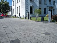 a sidewalk with a sidewalk marker, plants, and a bike in front of a building