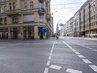 a street and intersection where people walk, and cars are parked in it as well