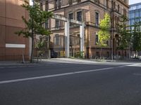 empty street with tall buildings in background and trees and bicycle path at bottom of photo