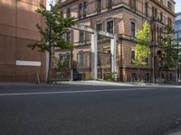 empty street with tall buildings in background and trees and bicycle path at bottom of photo