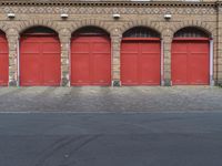 three fire hydrants in front of red doors on a brick building in an urban area