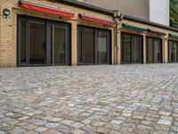 the bricked building with black doors has three red and green awnings over them