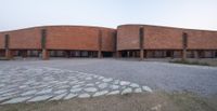 two circular shaped brick buildings sitting on top of a field next to each other,