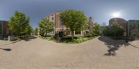 360 photograph looking up at a street with a building next to it and trees in the foreground