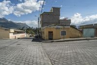 a woman walking down a street in front of buildings and mountains on a sunny day