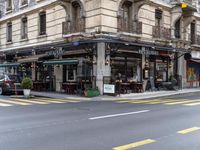 the building is on a street corner, and has many windows in it and some people are sitting at tables