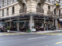 the building is on a street corner, and has many windows in it and some people are sitting at tables