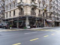 the building is on a street corner, and has many windows in it and some people are sitting at tables