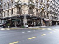 the building is on a street corner, and has many windows in it and some people are sitting at tables