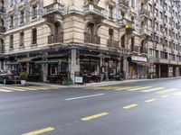 the building is on a street corner, and has many windows in it and some people are sitting at tables