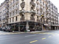 the building is on a street corner, and has many windows in it and some people are sitting at tables