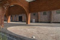 the empty courtyard area in this building features a red brick wall and arched arches that span the length of the front door