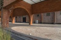 the empty courtyard area in this building features a red brick wall and arched arches that span the length of the front door