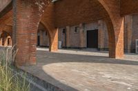 the empty courtyard area in this building features a red brick wall and arched arches that span the length of the front door