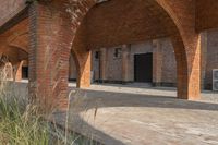 the empty courtyard area in this building features a red brick wall and arched arches that span the length of the front door