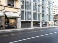 there is a picture of an empty city street in front of a tall building with open doors