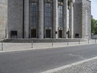 an old building with some columns on the side and a street in front of it