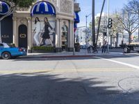 people are walking down the road near a store with blue and white awnings