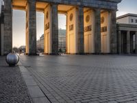 a person sits on top of a stone floor next to a street with pillars in the background