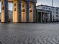 a person sits on top of a stone floor next to a street with pillars in the background