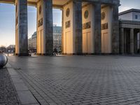 a person sits on top of a stone floor next to a street with pillars in the background