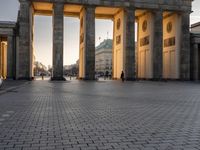 a person sits on top of a stone floor next to a street with pillars in the background