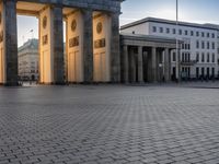 a person sits on top of a stone floor next to a street with pillars in the background