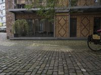 a fire hydrant stands in front of a bricked courtyard with patio chairs and tables