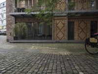 a fire hydrant stands in front of a bricked courtyard with patio chairs and tables
