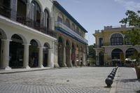 a stone paved street that has columns and blue awnings around the building on either side