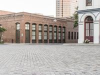 a brick road with old windows and buildings in the background and an empty area on the ground