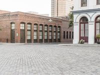 a brick road with old windows and buildings in the background and an empty area on the ground