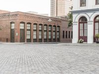 a brick road with old windows and buildings in the background and an empty area on the ground