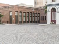 a brick road with old windows and buildings in the background and an empty area on the ground