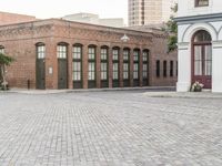 a brick road with old windows and buildings in the background and an empty area on the ground